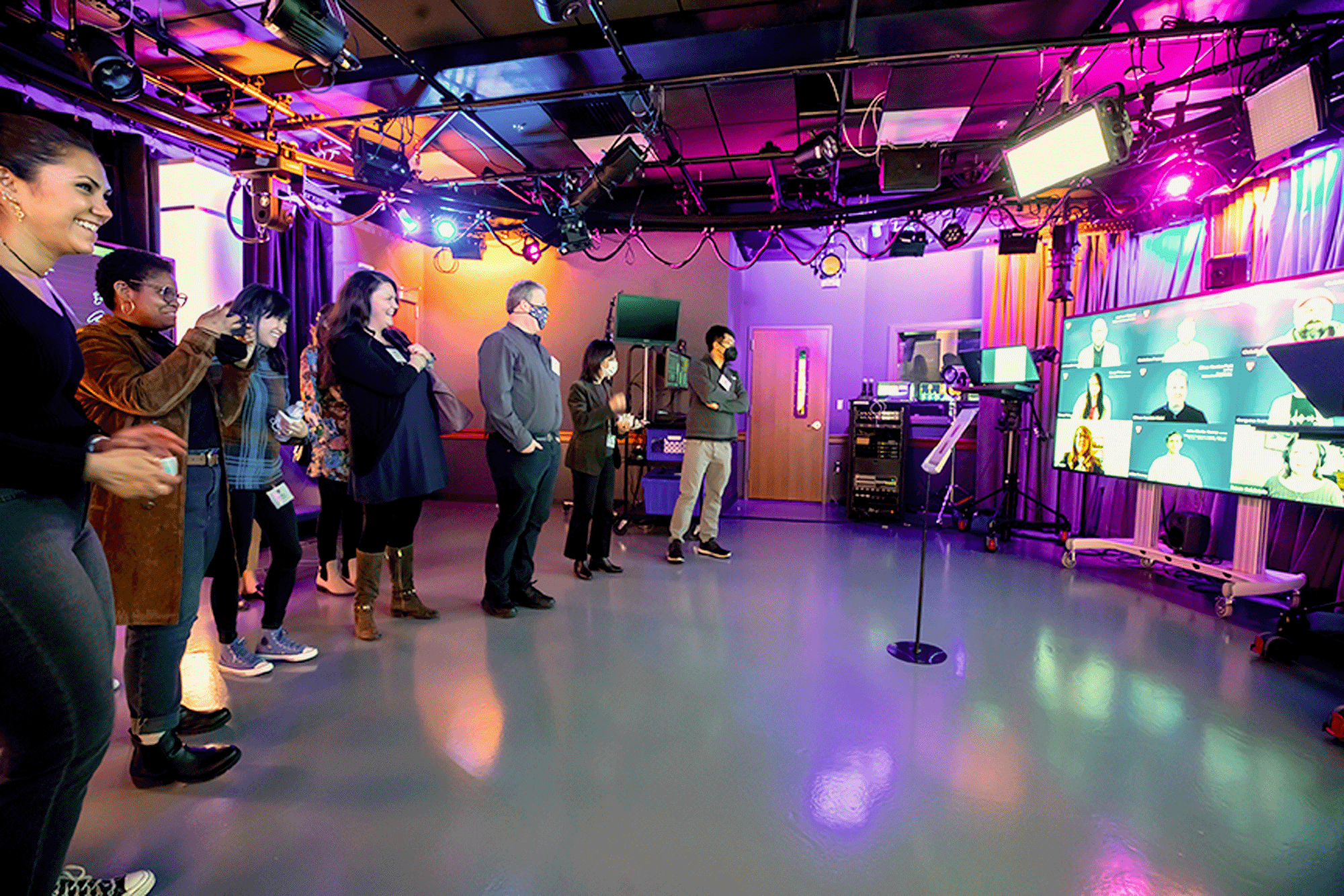 A group of people admire a state-of-the-art production studio with multiple large screens showing a zoom meeting in PDP's new teaching spaces.